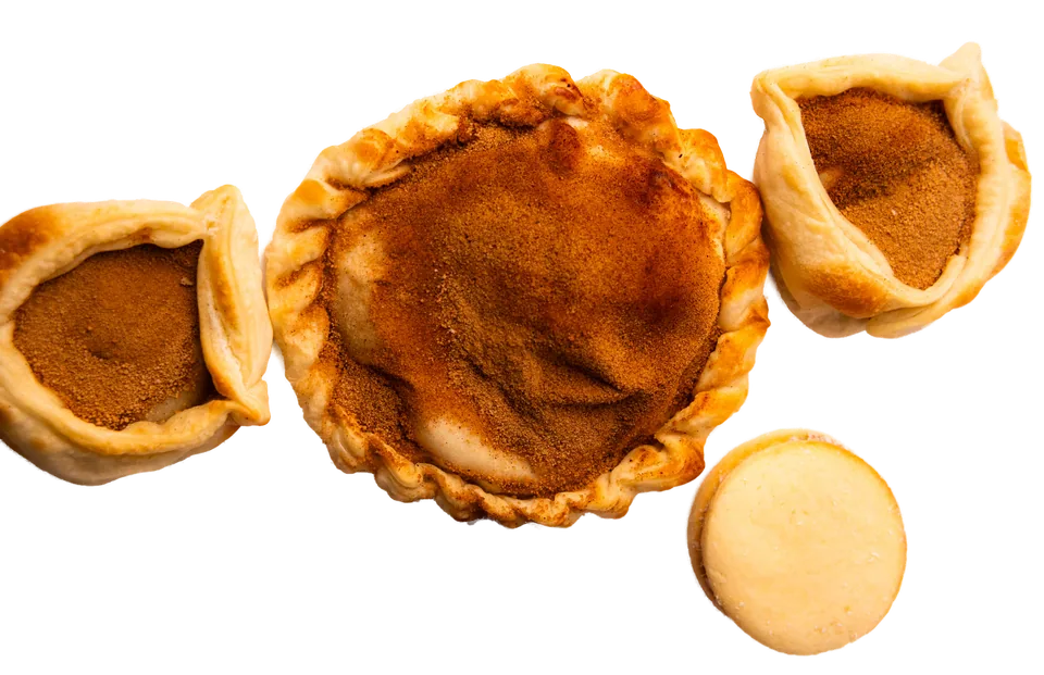 Empanadas doces abertas com canela, ao lado de alfajores de chocolate e de maizena